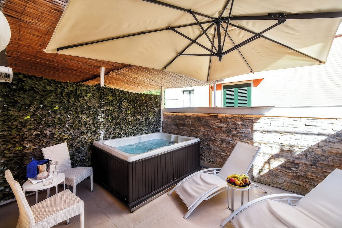 Un bain à remous, un espace salon extérieur et un mur en pierre.