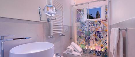 A modern bathroom with a large white sink, a bidet, and a glass shower enclosure.