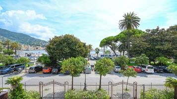 A parking lot with several cars, trees, and a gate.