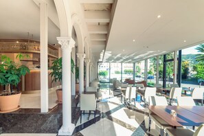 A modern hotel lobby with a bar area, seating, and large windows offering a view of the outdoors. - Hotel Astoria Rapallo (Rapallo)