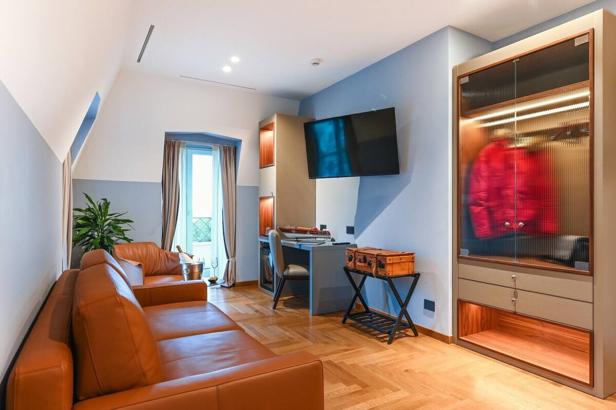 Una sala de estar moderna con un sofá, una televisión, un escritorio y un vestidor con una percha.