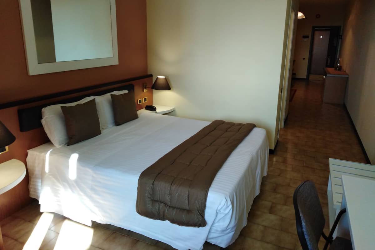 Une chambre d’hôtel avec un grand lit, des tables de chevet, un bureau et une chaise.