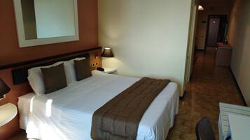 A hotel room with a large bed, bedside tables, a desk, and a chair.