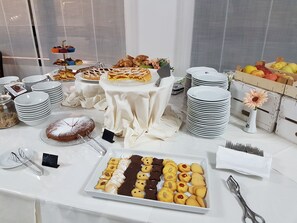 A buffet table with various food items, plates, and utensils. - RHI Porta Bologna (Pieve di Cento)