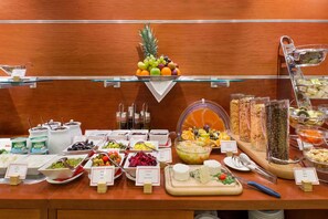 Un buffet proposant une variété de plats, notamment des fruits, des fromages et des salades.