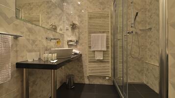 A modern bathroom with a glass shower enclosure, a black countertop sink, and a towel rack.