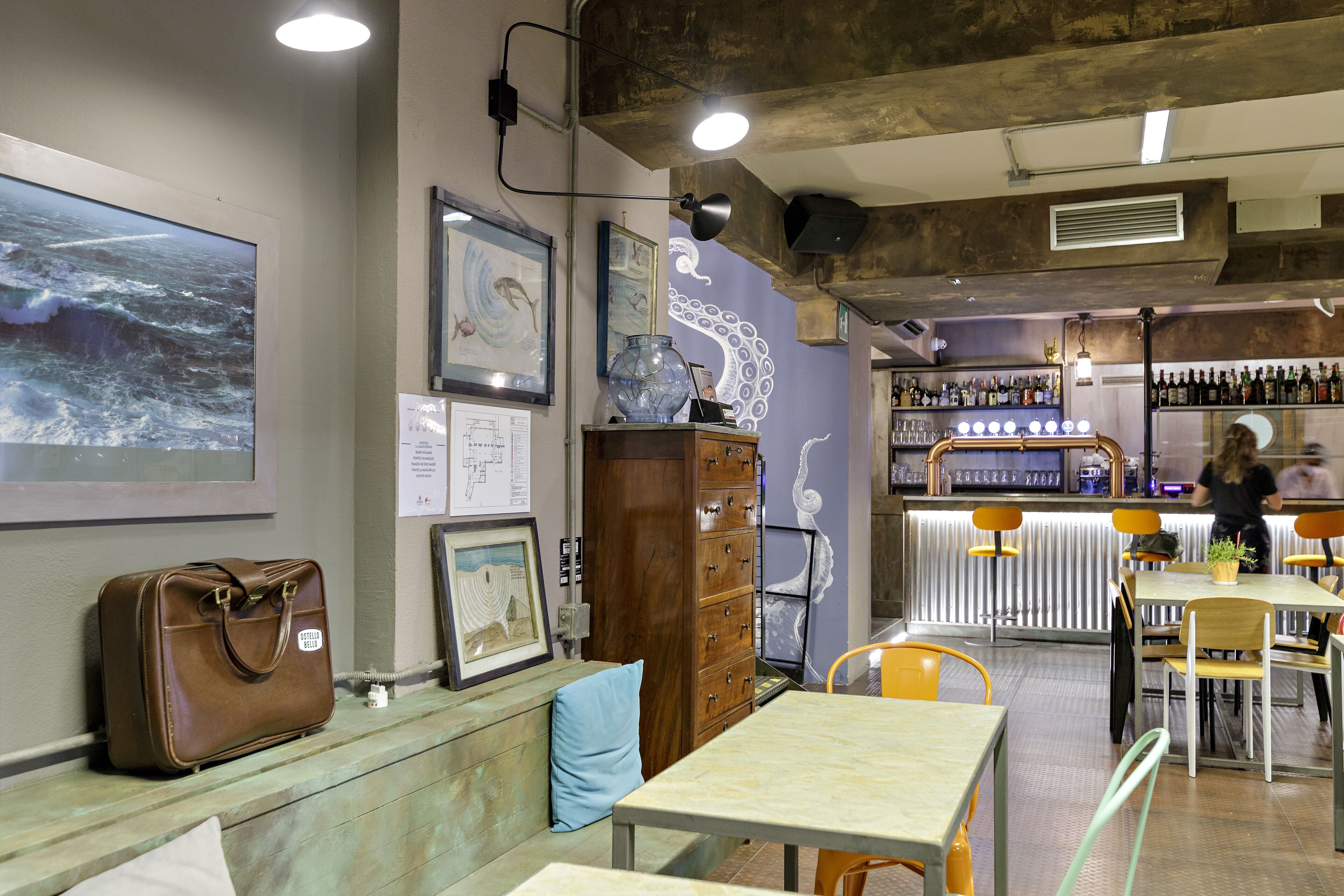 Interior de un restaurante con mesas, sillas, una zona de bar y diversas decoraciones en las paredes.