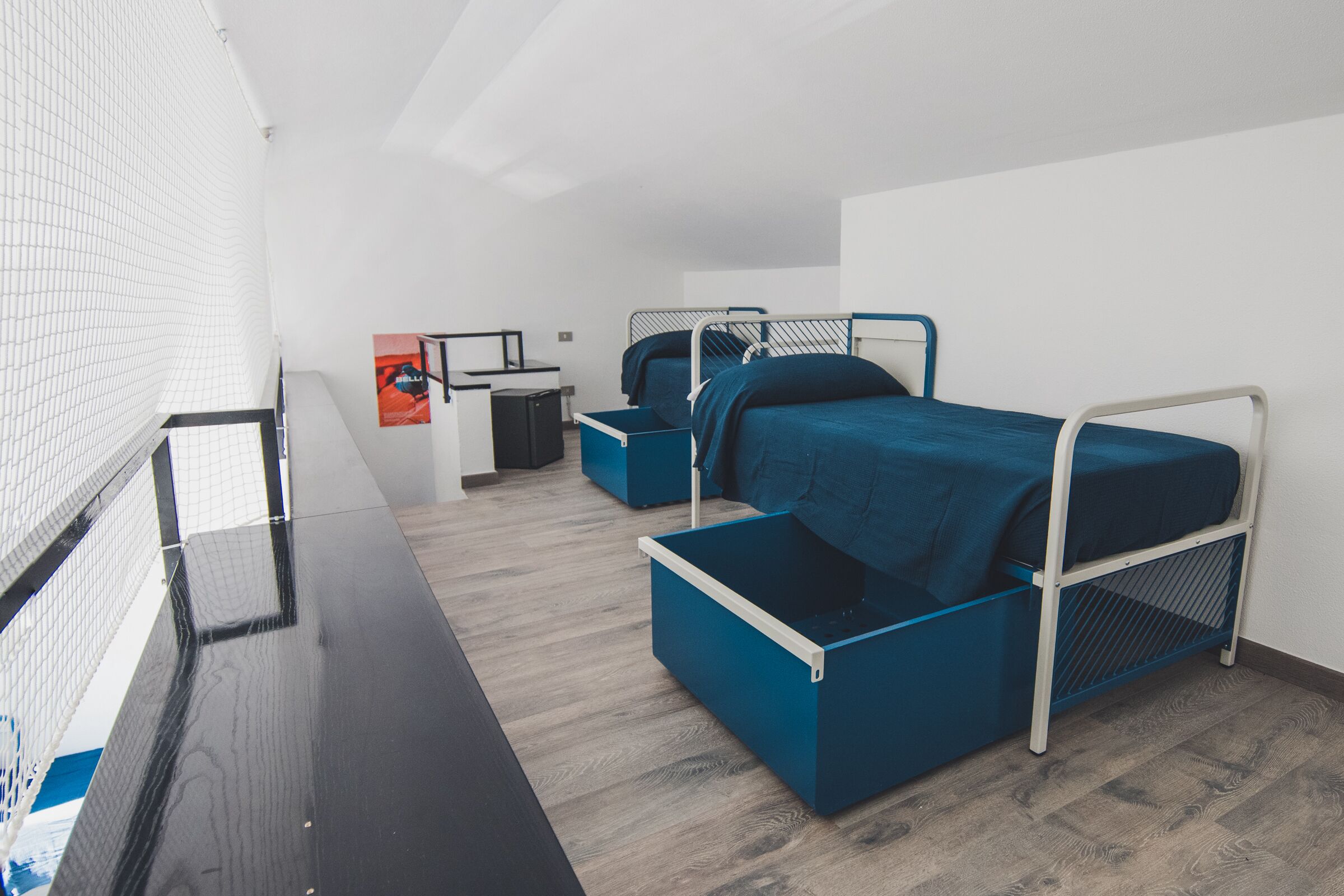 Een moderne hotelkamer met een stapelbed, een bureau met stoel, en een kleine kitchenette.