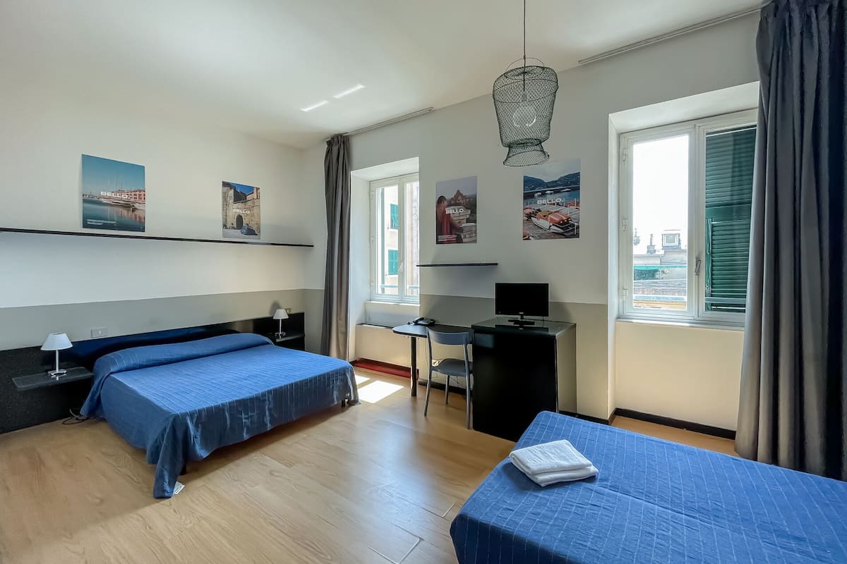 Hotellihuone, jossa on kaksi sänkyä, työpöytä, tuoli ja televisio.