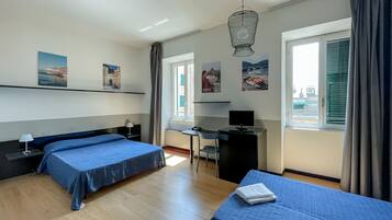 Une chambre d’hôtel avec deux lits, un bureau, une chaise et un téléviseur.