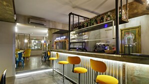 A bar area with stools, a shelf with bottles, and a cash register.