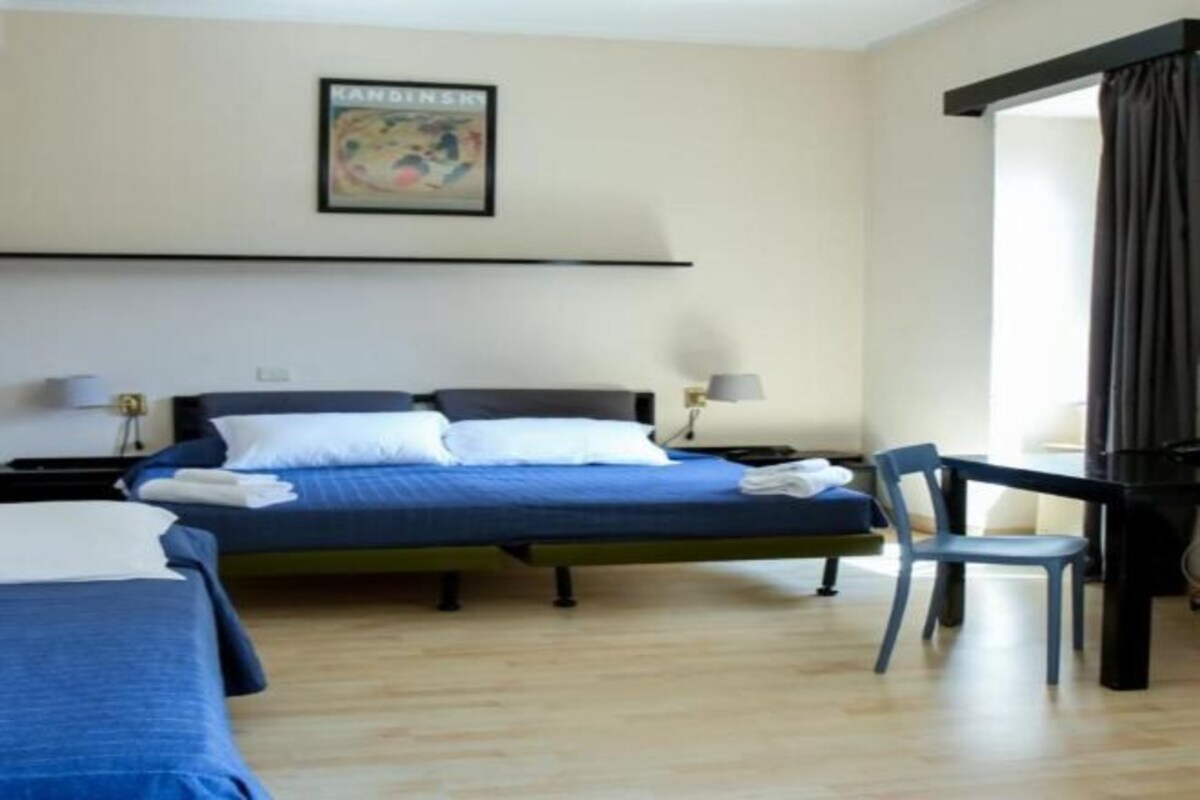 A hotel room with a bed, two bedside tables, a chair, and a desk.