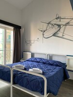 A bedroom with a bed, a window with curtains, and a wall with a mural of airplanes.