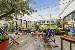 Un espace extérieur aménagé en terrasse, avec un sol en bois, divers types de sièges, notamment des chaises et des tables, et des plantes en pot.
