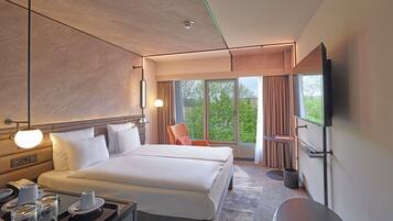 A modern hotel room with a large bed, bedside tables, a desk with a telephone, and a TV mounted on the wall.