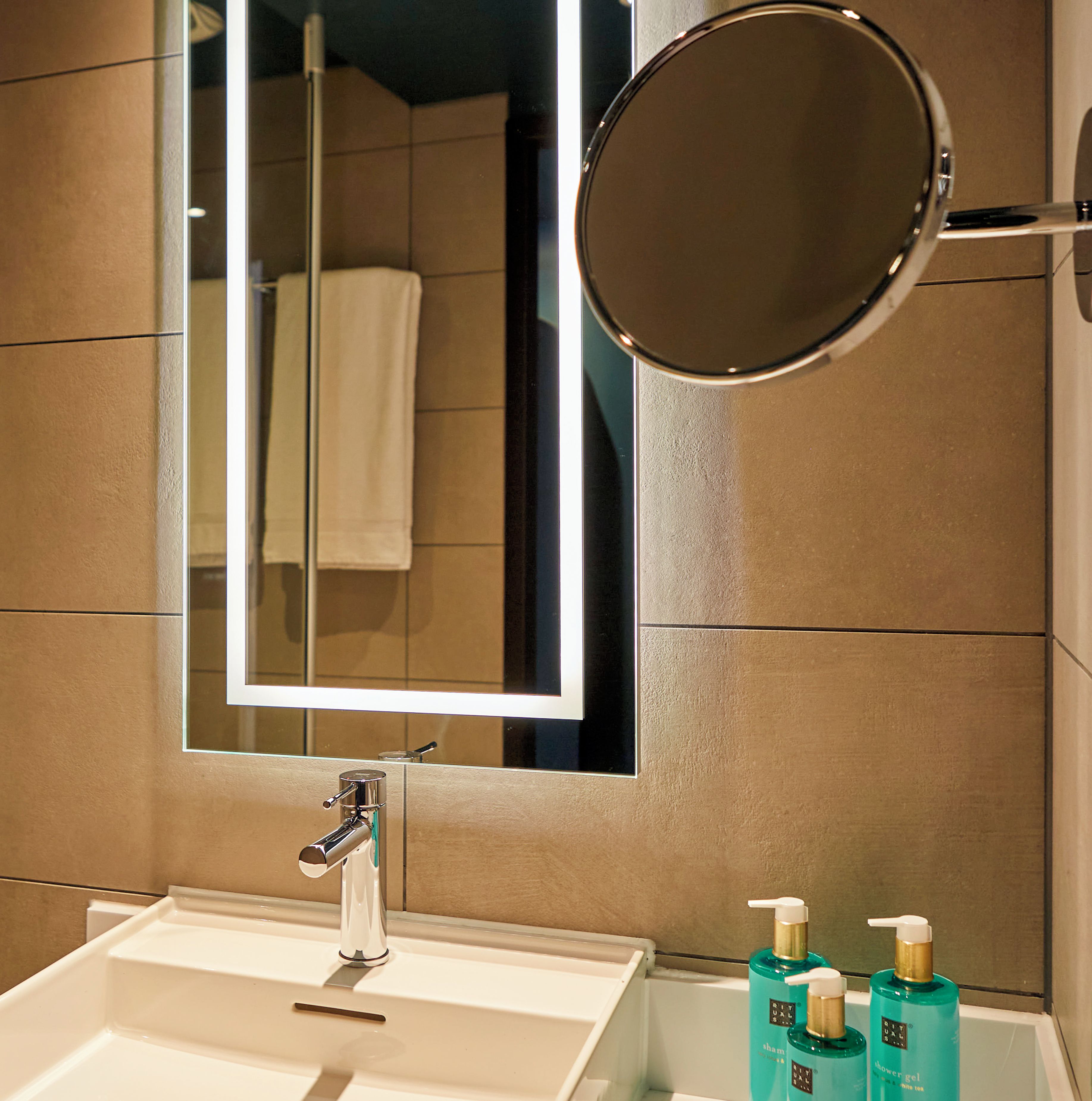 Een badkamer met een wastafel, spiegel en twee shampoo flessen.