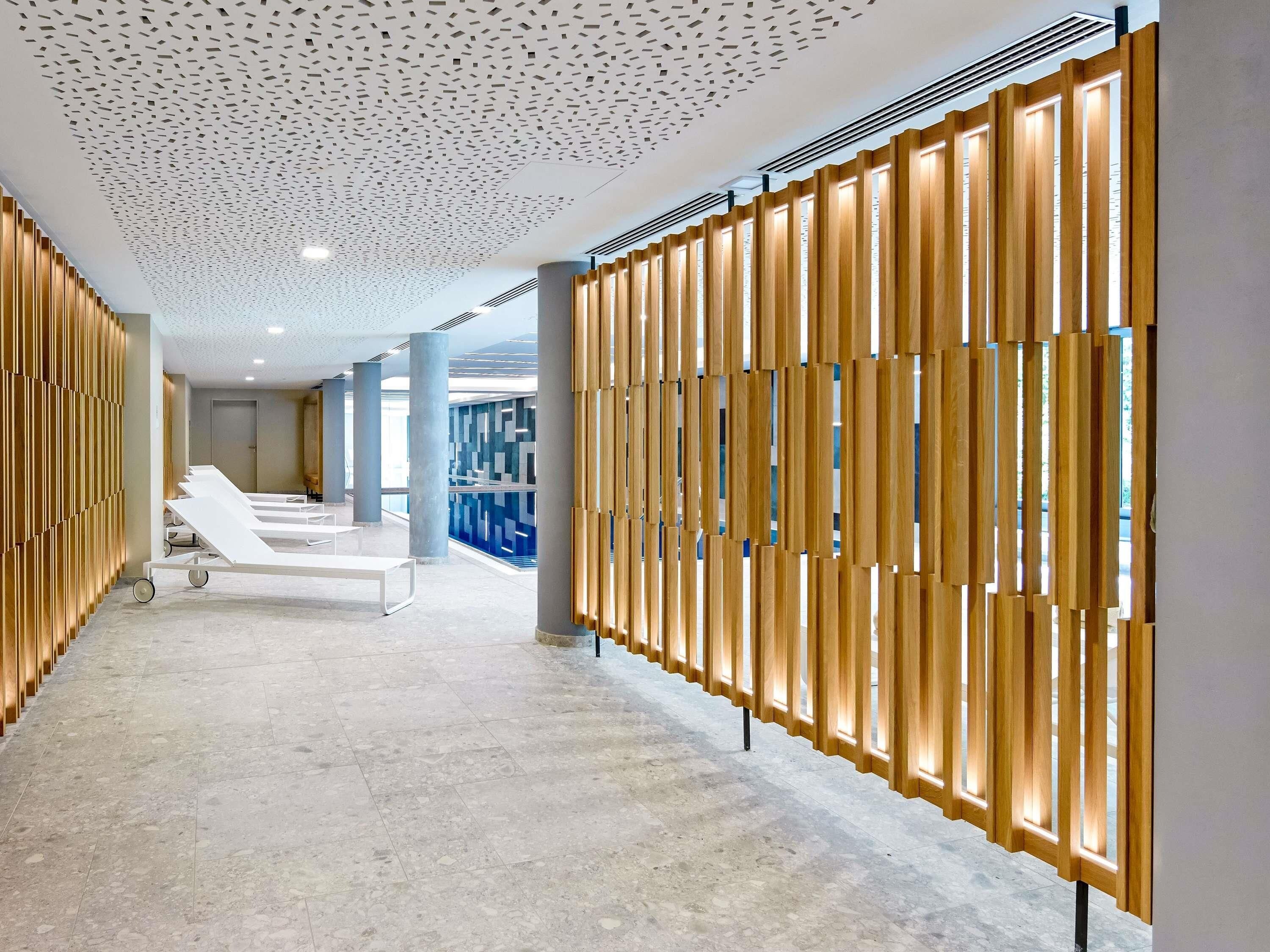Un pasillo con diseño moderno, que destaca por un techo con motivos, paredes de listones de madera y un suelo de baldosas.