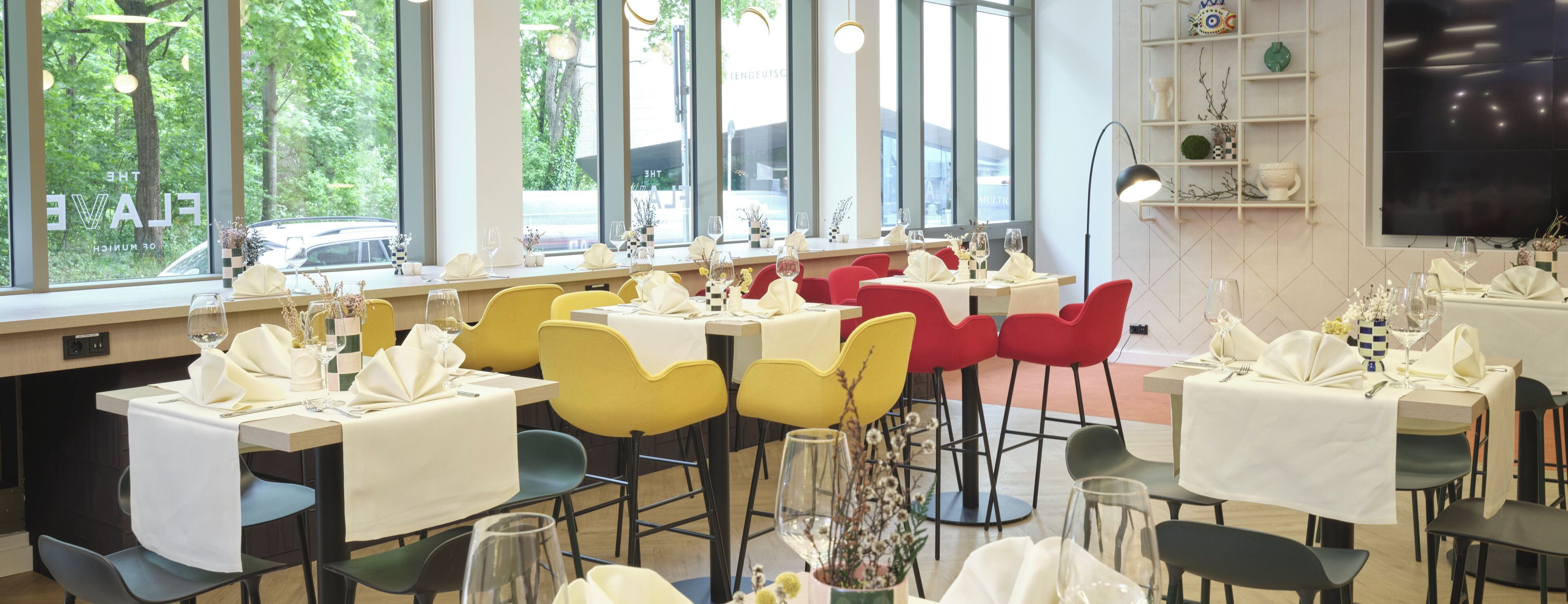 Un restaurante con mesas listas para comer, ventanas amplias y vista a la calle.