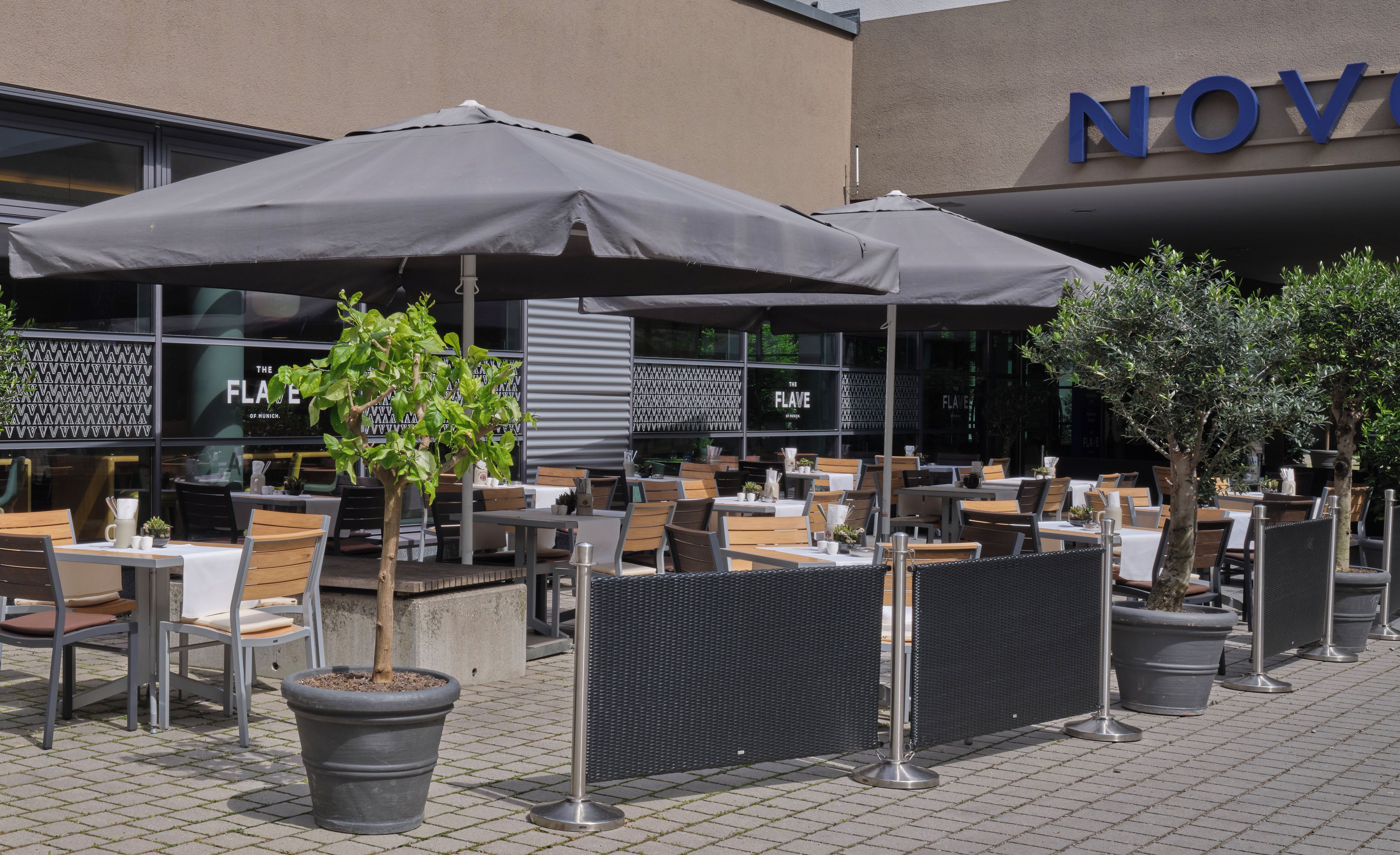 An outdoor seating area with tables and chairs, umbrellas, and potted plants.