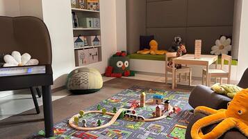 A child's playroom with a train set, plush toys, and a bookshelf.