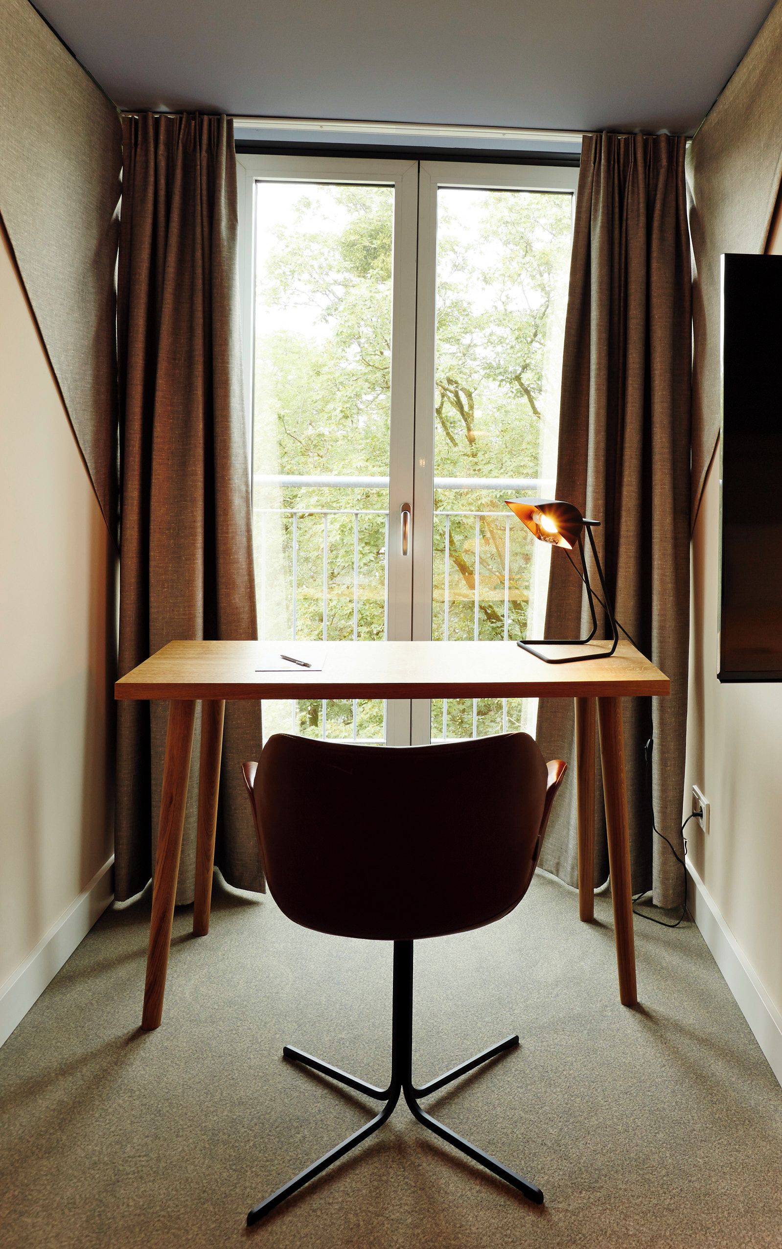 A room with a desk, chair, and a window with curtains.