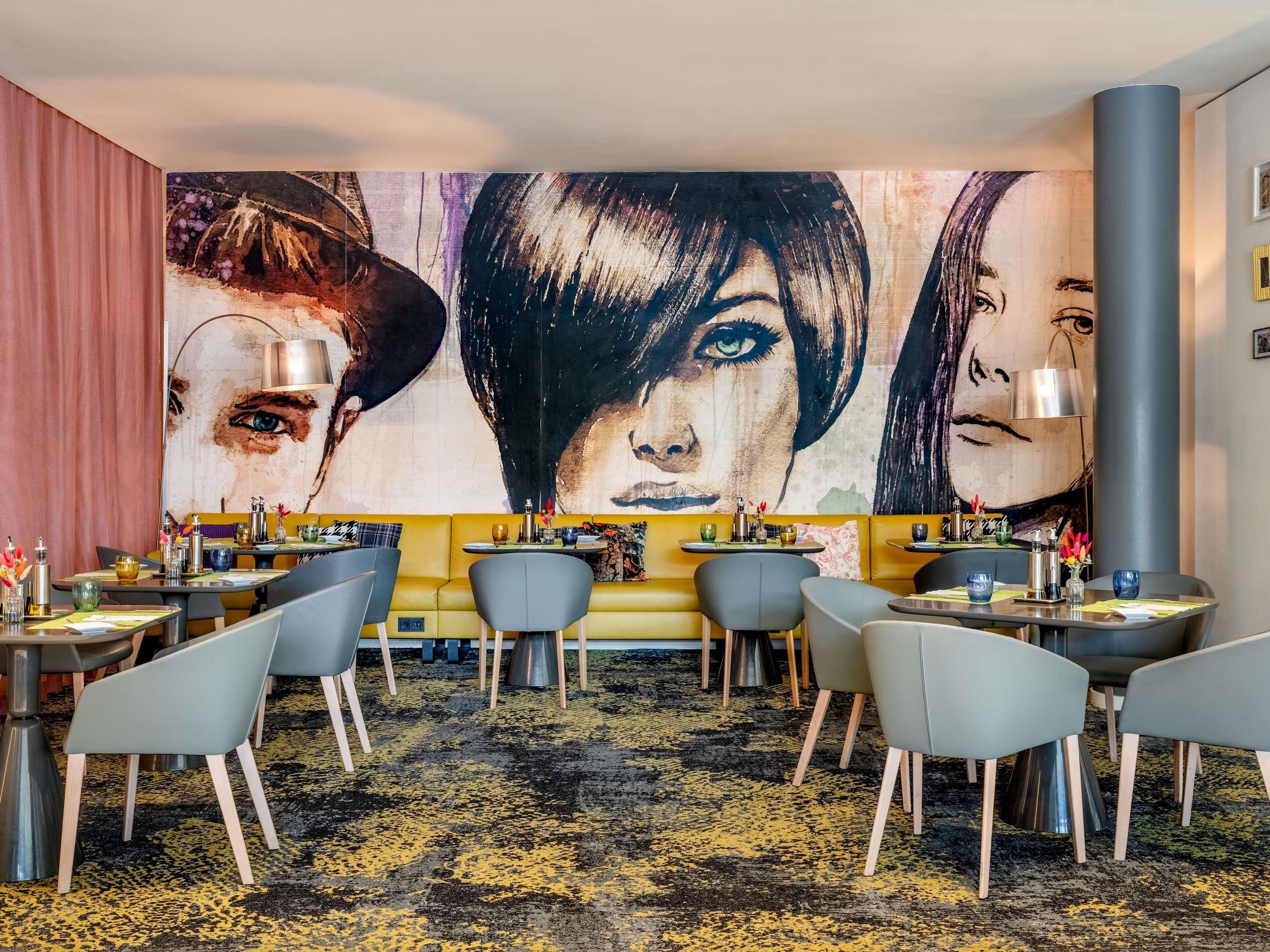 Ein Restaurant mit einer großen Wandmalerei, mehreren Tischen und Stühlen.