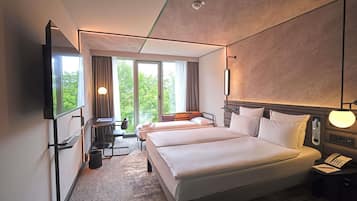 Ein Hotelzimmer mit einem großen Bett, einem Schreibtisch mit Stuhl, einem Fernseher und einem Fenster mit Vorhängen.