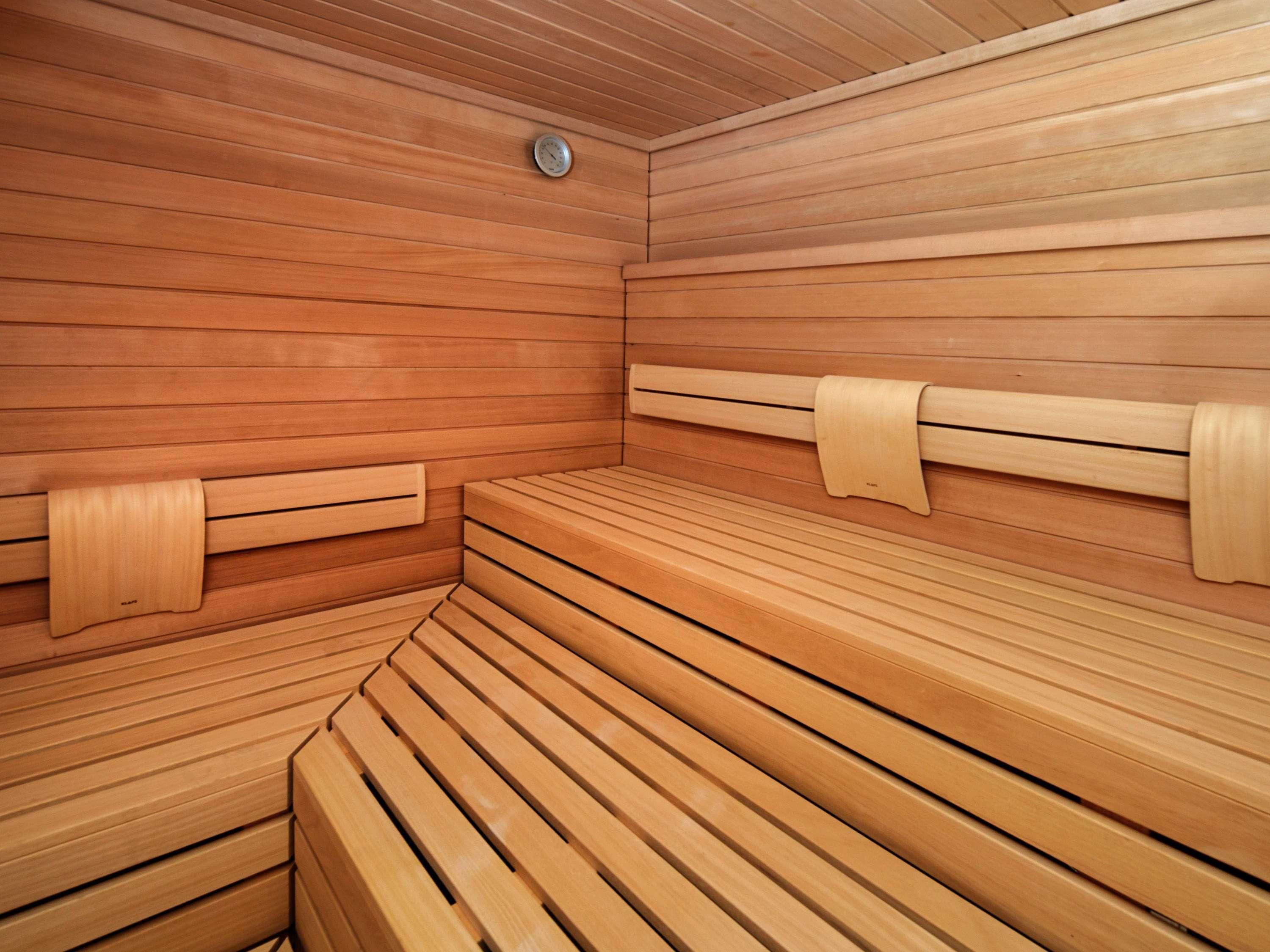 A sauna with wooden benches and benches with towel holders.
