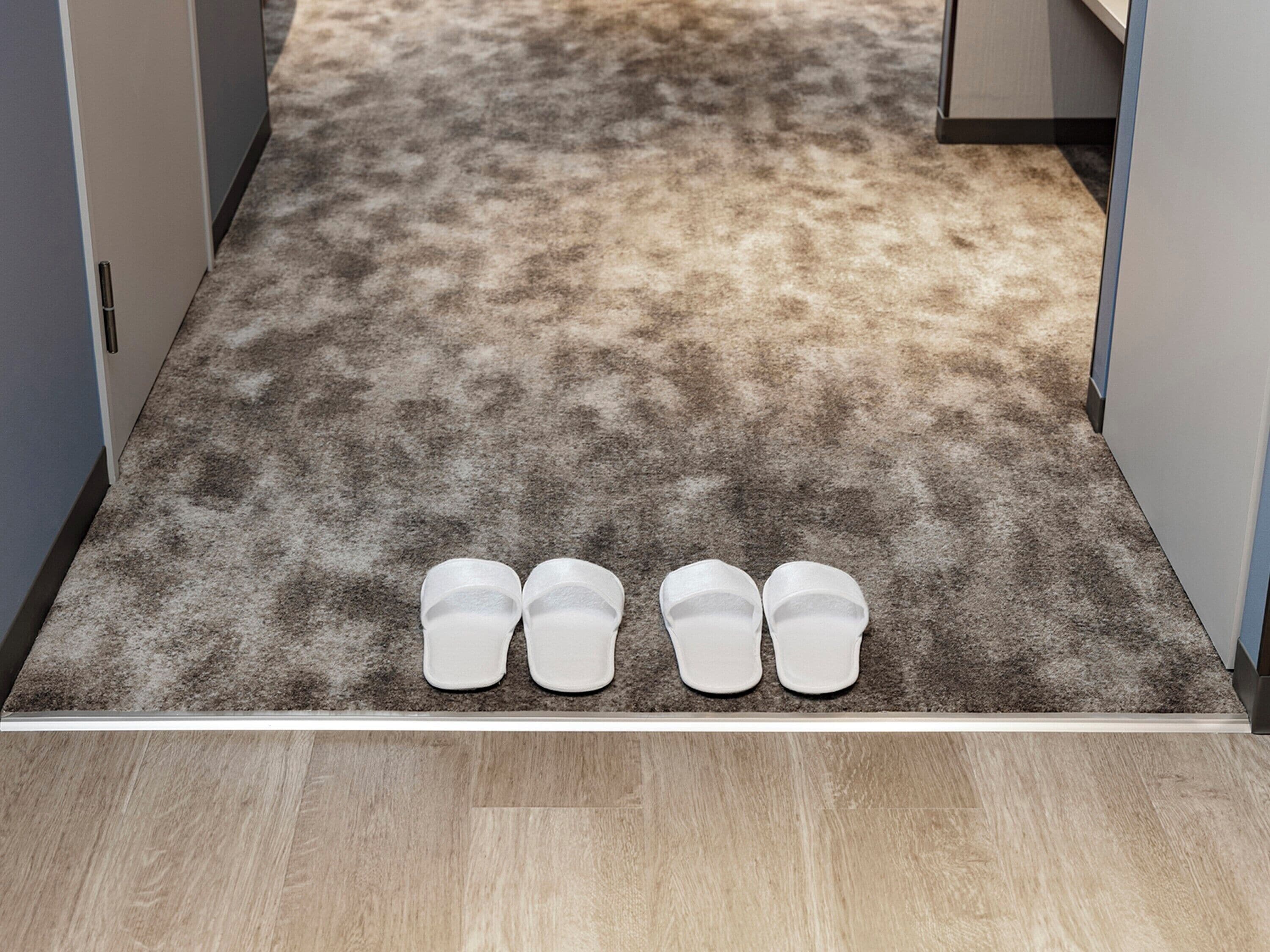 Un couloir recouvert de moquette, avec un plancher en bois et une porte sur le côté droit.