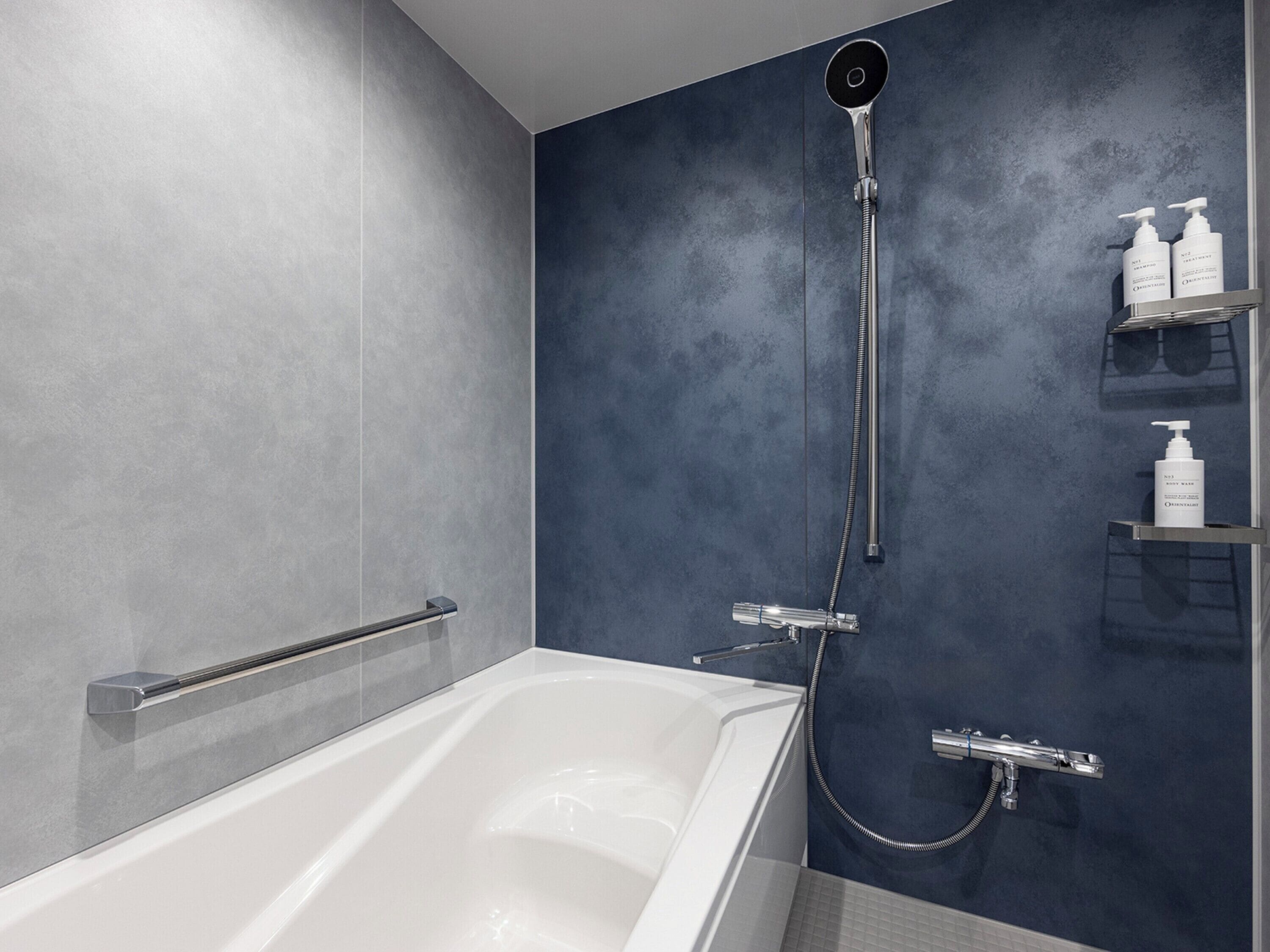 Une salle de bain moderne équipée d’une baignoire, d’une douchette et d’une étagère murale où sont rangés les articles de toilette.
