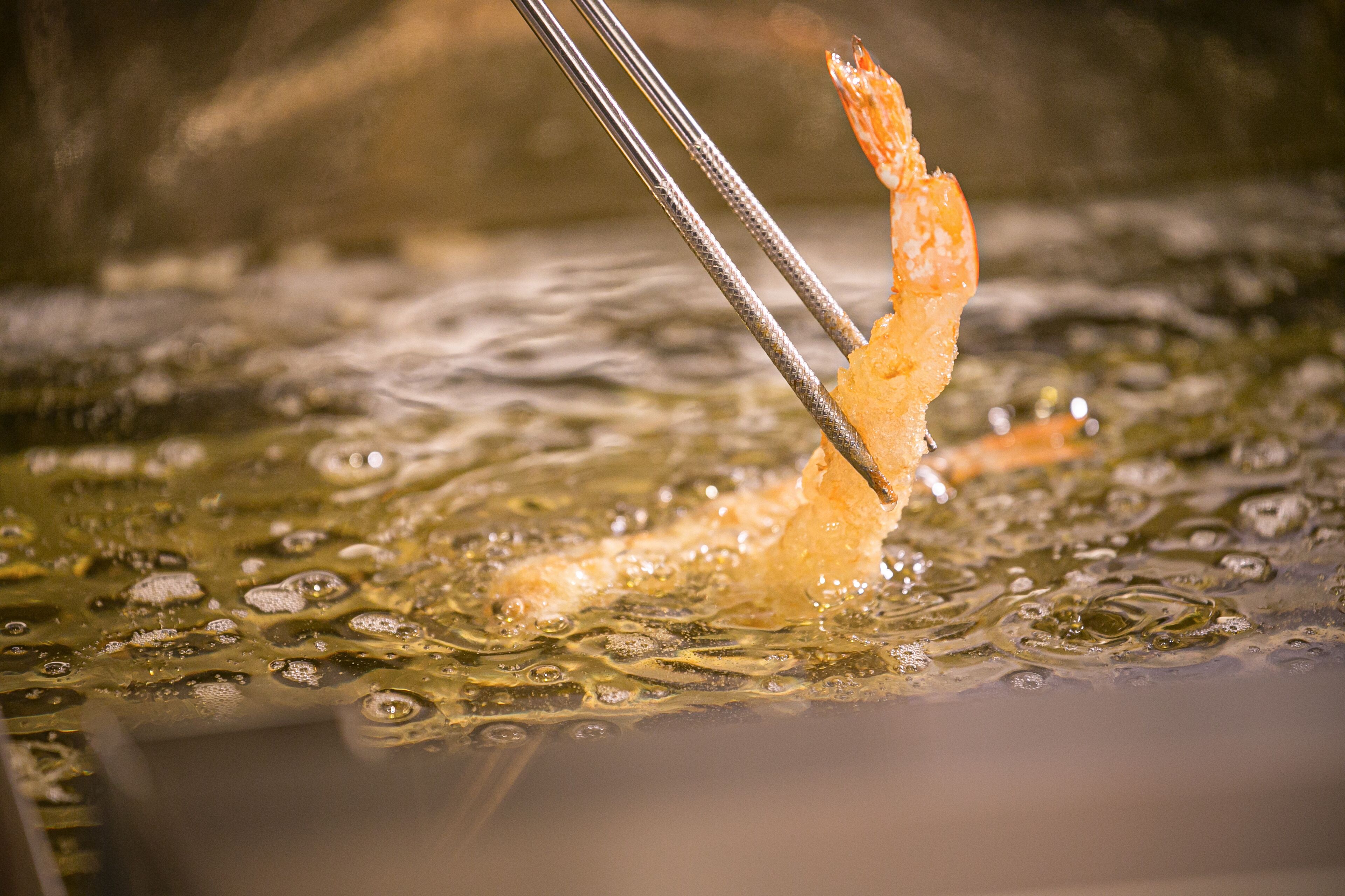 A close-up of a shrimp being fried in hot oil.