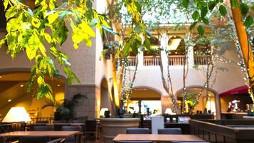 An indoor dining area with tables and chairs, a balcony with railings, and string lights.