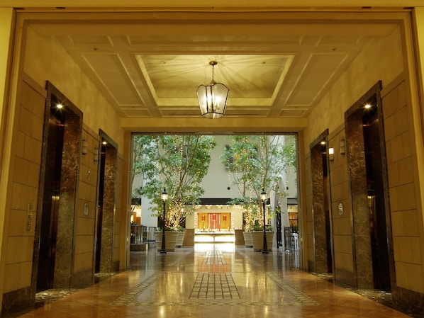 A spacious lobby with marble flooring, a central chandelier, and a view of a restaurant through a glass wall. - Oriental Hotel Tokyo Bay (Urayasu)