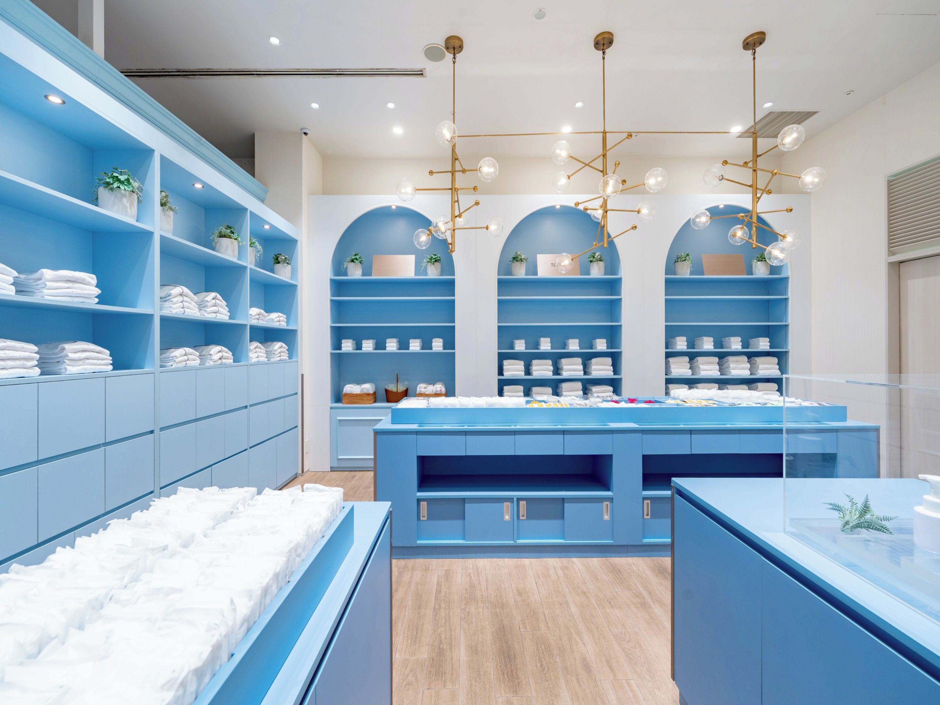 A modern retail store with blue shelving, white towels, and a central display table.