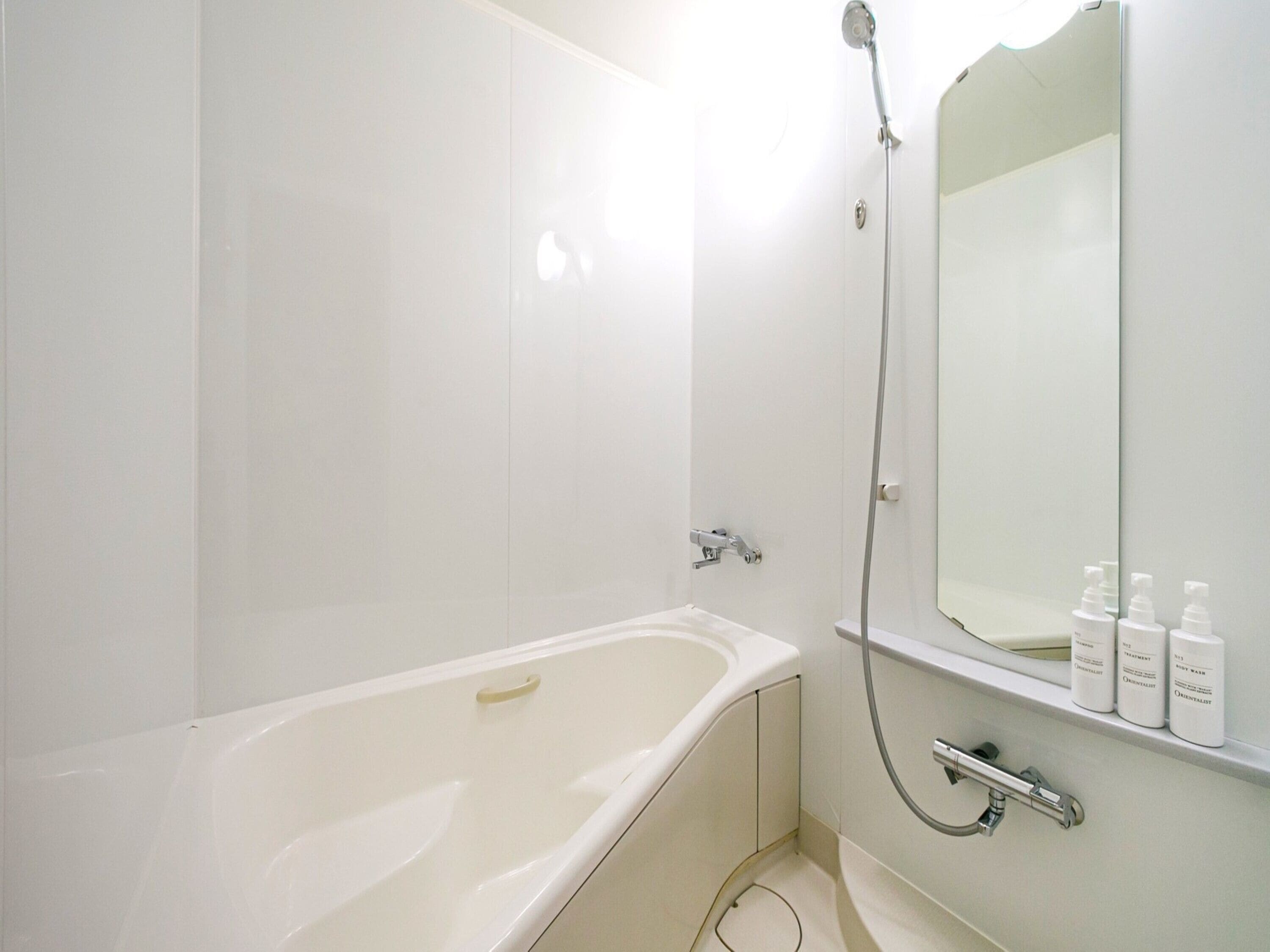 A modern bathroom with a bathtub, a shower, and a mirror.