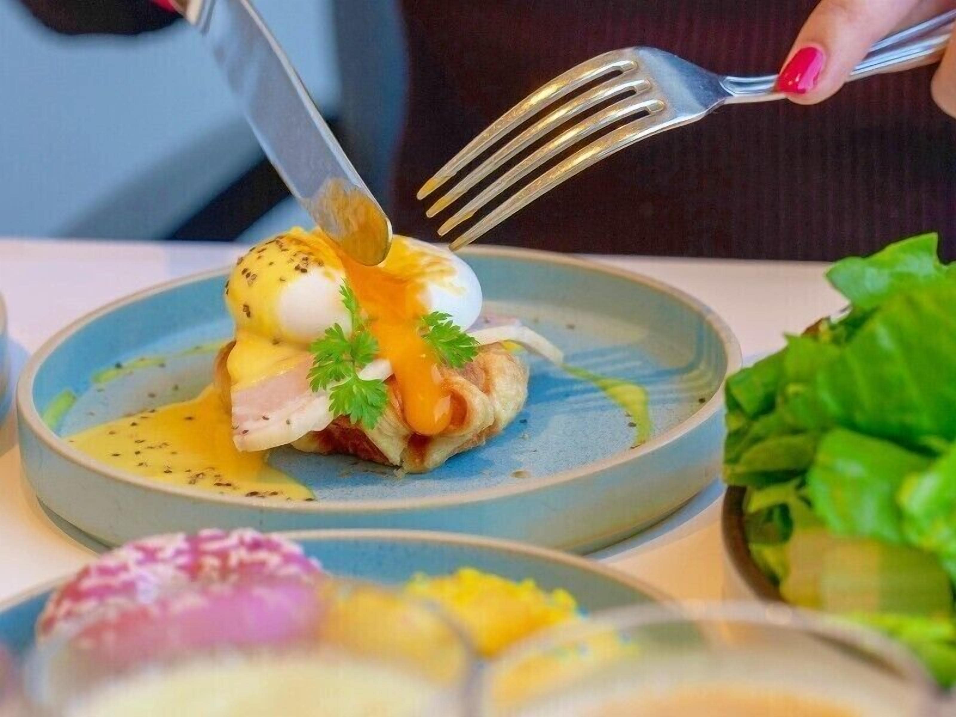 Une table à manger avec une assiette de nourriture, une fourchette et une salade.