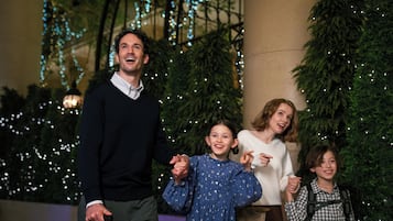 A family of four in front of a decorated Christmas tree with lights.
