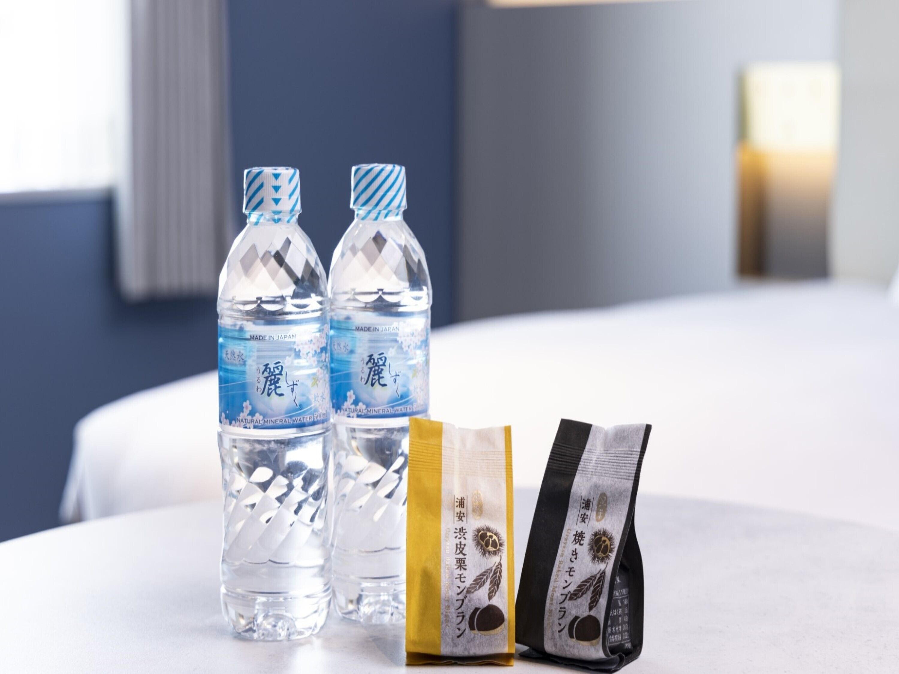 Two water bottles and two snack packets on a table in a hotel room.