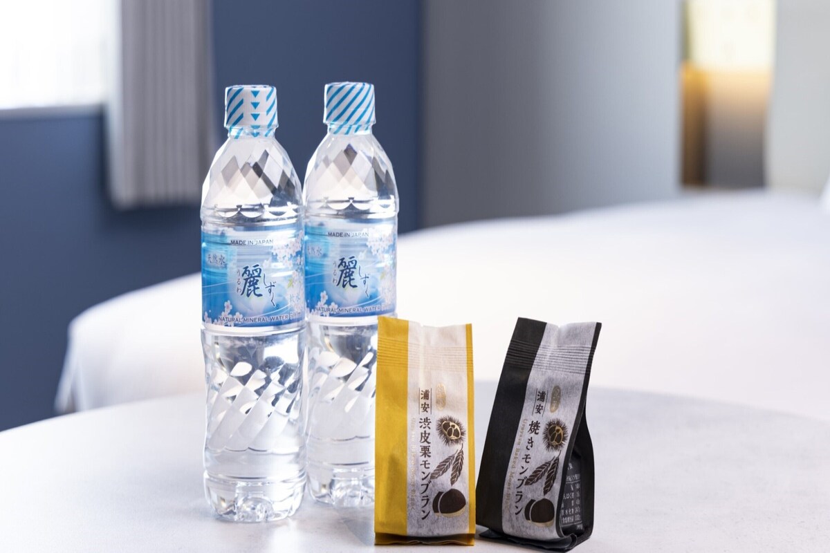 Two water bottles and two snack packets on a table in a hotel room.