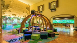 A lobby with a central seating area, a large aquarium, and a stone wall with a mural.