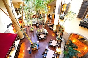 Un atrium intérieur doté d’un plancher en bois, de plusieurs espaces aménagés pour s’asseoir et de plantes en pot.