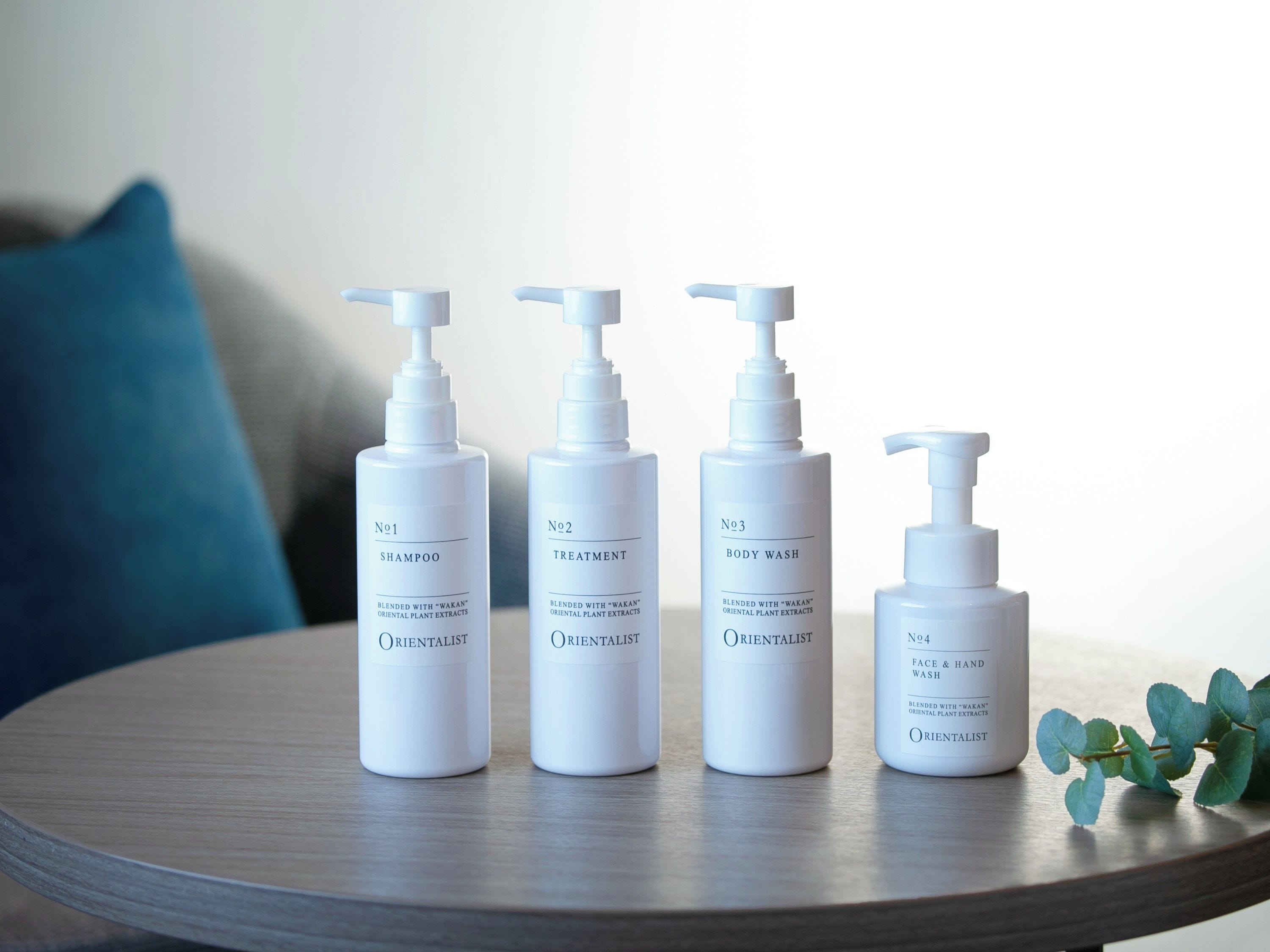 Four bottles of Orientalist skincare products on a round wooden table.