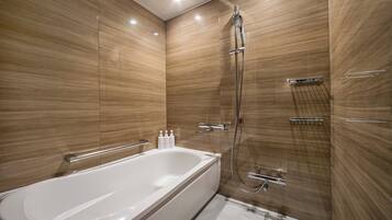 A modern bathroom with a large bathtub, a shower with a handheld showerhead, and a glass-enclosed shower area.