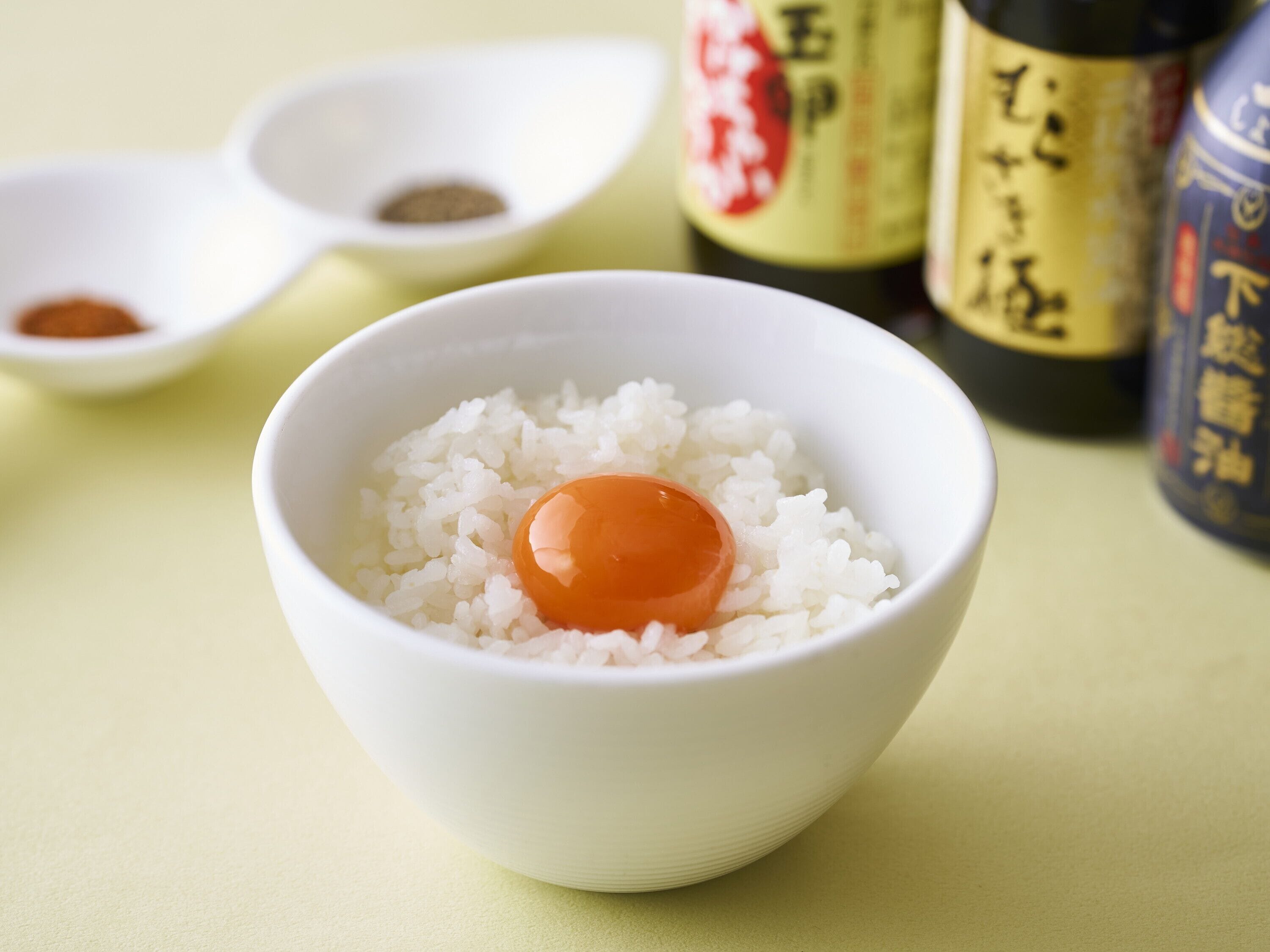 Un bol de riz blanc avec un œuf au centre, entouré de différentes sauces et condiments.