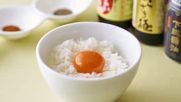 Un bol de riz blanc avec un œuf au centre, entouré de différentes sauces et condiments.