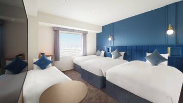 Habitación de hotel con dos camas, una mesita redonda y vista a la ciudad.