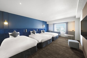A hotel room with three beds, a small table, and a view of the city. - Oriental Hotel Tokyo Bay (Urayasu)