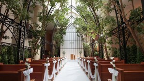 Ein Kircheninneres mit in Reihen angeordneten Kirchenbänken, einer zentralen Mittelschiffgasse und einer hohen Decke mit schmiedeeisernen Verzierungen.
