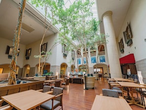 A spacious indoor area with multiple tables and chairs, a high ceiling, and several trees. - Oriental Hotel Tokyo Bay (Urayasu)