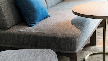 Un canapé gris avec un coussin bleu et une table basse ronde en bois.